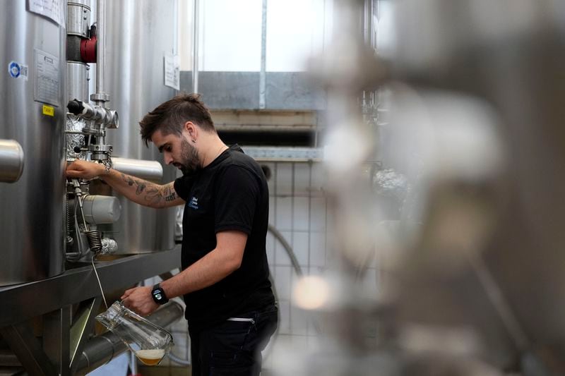 An employee of the Technical University of Munich fills beer in the brewery in Freising, Germany, Thursday, Sept. 19, 2024. (AP Photo/Matthias Schrader)