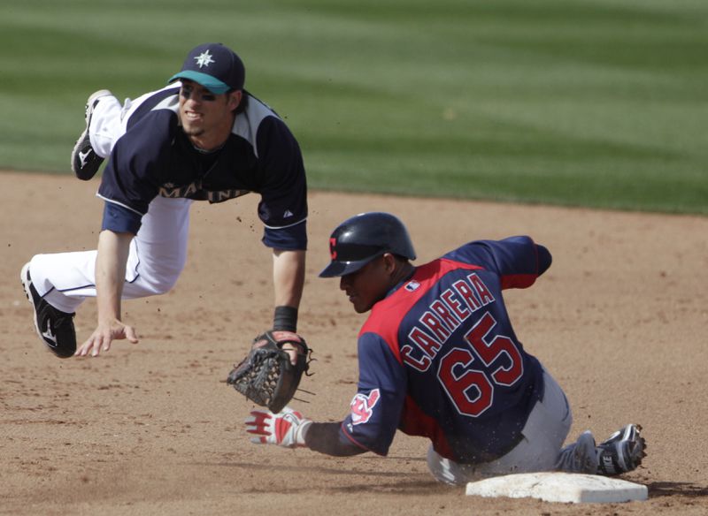 Seattle Mariners second baseman Sean Kazmar hurdles Cleveland Indians' Ezequiel Carrera while relaying to first to complete a double play in the fifth inning of a spring training baseball game in Peoria, Ariz., Saturday, March 5, 2011. (AP Photo/Lenny Ignelzi)