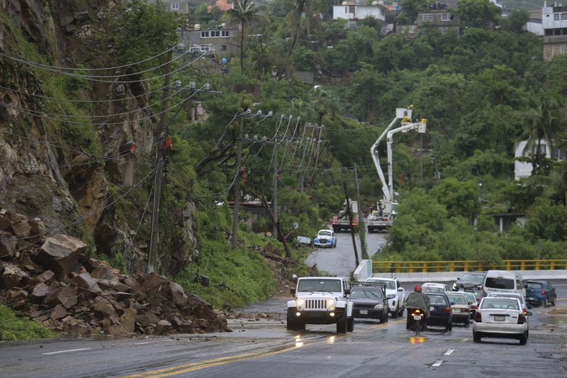 Residents drive past power lines damaged during the passing of Hurricane John, in Acapulco, Mexico, Friday, Sept. 27, 2024. (AP Photo/Bernardino Hernandez)