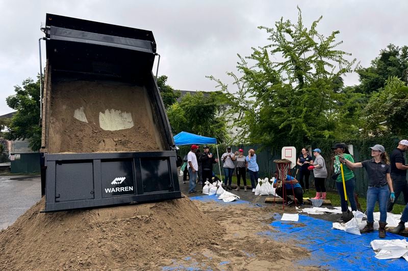 Residents fill up sand bags to protect their homes in anticipation of Tropical Storm Francine, Tuesday, Sept. 10, 2024, at a distribution site in a parking lot in New Orleans. (AP Photo/Jack Brook)