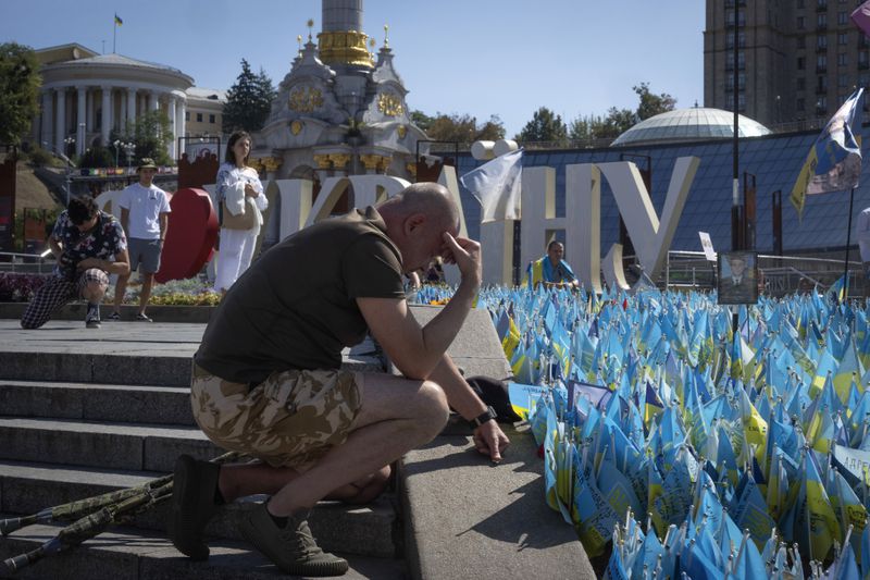 A veteran pays his respect at a makeshift memorial for fallen Ukrainian soldiers in the Russian-Ukrainian war during Ukrainian Independence Day on Independence Square in Kyiv, Ukraine, Saturday, Aug. 24, 2024. (AP Photo/Efrem Lukatsky)