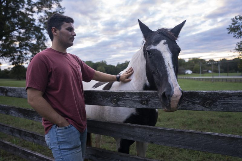 Edward Robertson greets his mother-in-law's horse, Coco, in Homer on Oct. 1, 2024. (Olivia Bowdoin for the AJC).