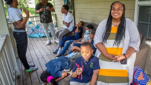 Tameka Stinson sits on the porch of her Atlanta home with her nine children, ages 7 to 19. While the affordable housing program covers her rent and electricity, an unexpected balance on her water bill put a strain on her finances, and she says that the child tax credit has helped pay for back-to-school items. “Kids always needs shoes, clothes, toiletries and stuff,’' Stinson said. (Steve Schaefer for The Atlanta Journal-Constitution)
