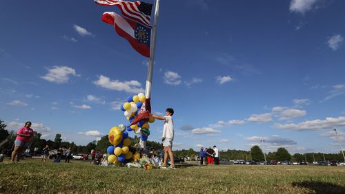 Conner Gandy, 24, puts a flag from Marjory Stoneman Douglas High School on the pole outside Apalachee High School in memory and respect for the victims on Thursday, Sept. 5, 2024. (Miguel Martinez / AJC)