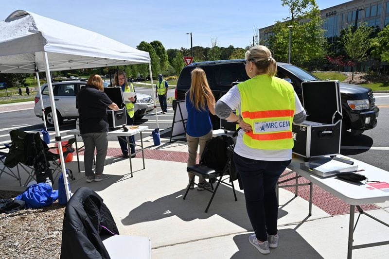 Health care workers help potential patients with their paperwork at a drive-thru COVID-19 testing site for anyone experiencing symptoms at the Infinite Energy Center in Duluth on Wednesday, April 22, 2020. It was the second large-scale testing event in a week conducted by the Gwinnett, Newton and Rockdale County Health Department. (Hyosub Shin / Hyosub.Shin@ajc.com)