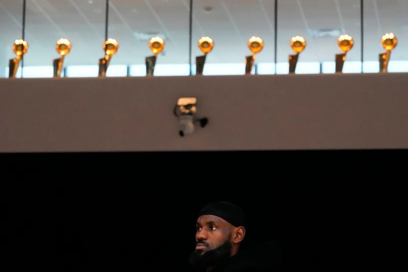 Championship trophies line along the window as Los Angeles Lakers' LeBron James attends a news conference held to introduce the team's draft picks, Bronny James and Dalton Knecht, in El Segundo, Calif., Tuesday, July 2, 2024. (AP Photo/Damian Dovarganes)
