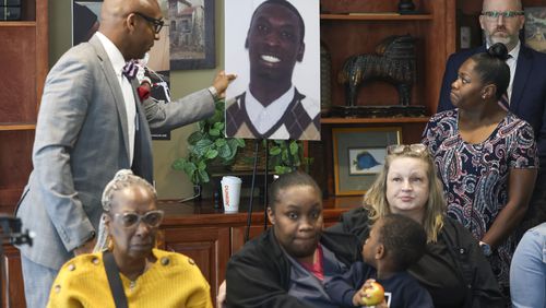 Attorney Mawuli Davis, left, displays a photograph of the late Dino Walker in front of his family during a press conference for Walker, a Fulton inmate, who was stabbed to death at the Fulton County Jail in 2022, at the office of Davis Bozeman Johnson Law, Thursday, September 21, 2023, in Decatur, Ga. (Jason Getz / Jason.Getz@ajc.com)