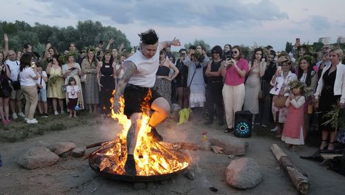 A Ukrainian man jumps over fire during a traditional Ukrainian celebration of Kupala Night, in Warsaw, Poland, on Saturday, June 22, 2024. Ukrainians in Warsaw jumped over a bonfire and floated braids to honor the vital powers of water and fire on the Vistula River bank Saturday night, as they celebrated their solstice tradition of Ivan Kupalo Night away from war-torn home. (AP Photo/Czarek Sokolowski)