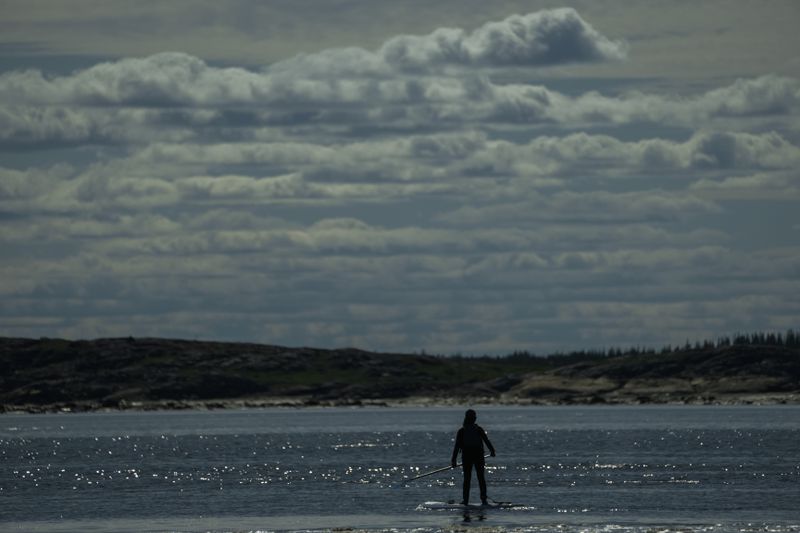 Erin Greene, center, owner of Sup North, stands on her paddleboard in the Churchill River while leading a tour, Thursday, Aug. 8, 2024, in Churchill, Manitoba. (AP Photo/Joshua A. Bickel)