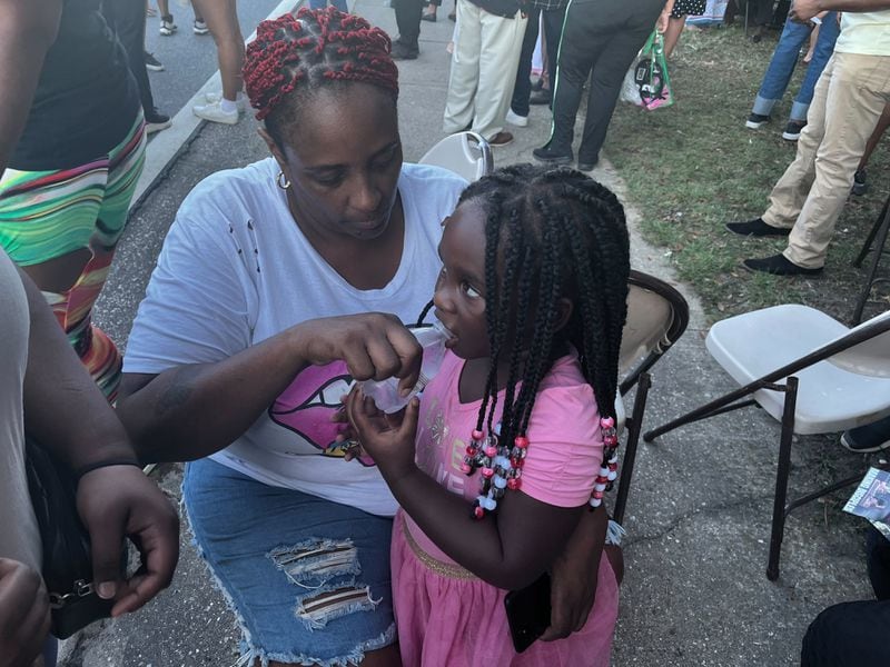 Sabrina Rozier gives water to the 4-year-old daughter of shooting victim Jarrald De’Shaun Gallion at the vigil on Sunday, August 27, 2023.