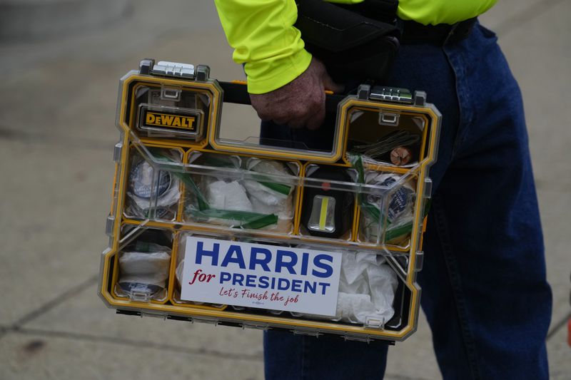 James Eckstein who is campaigning for Democratic presidential nominee Vice President Kamala Harris, holds is organizer containing sticker and buttons at the Butler Fall Festival in Butler, Saturday, Sept. 28, 2024. (AP Photo/Matt Rourke)