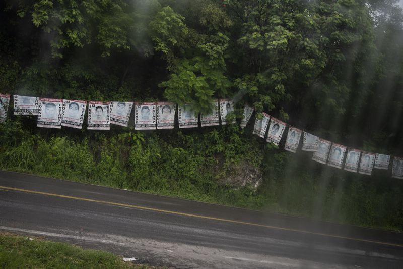 Posters of the 43 missing students from the Raúl Isidro Burgos Rural Normal School hang on the roadside, seen from the bus of their families who are traveling from Tixtla, Guerrero state, to the capital to protest for justice 10 years since their disappearance, Sunday, Aug. 25, 2024. (AP Photo/Felix Marquez)