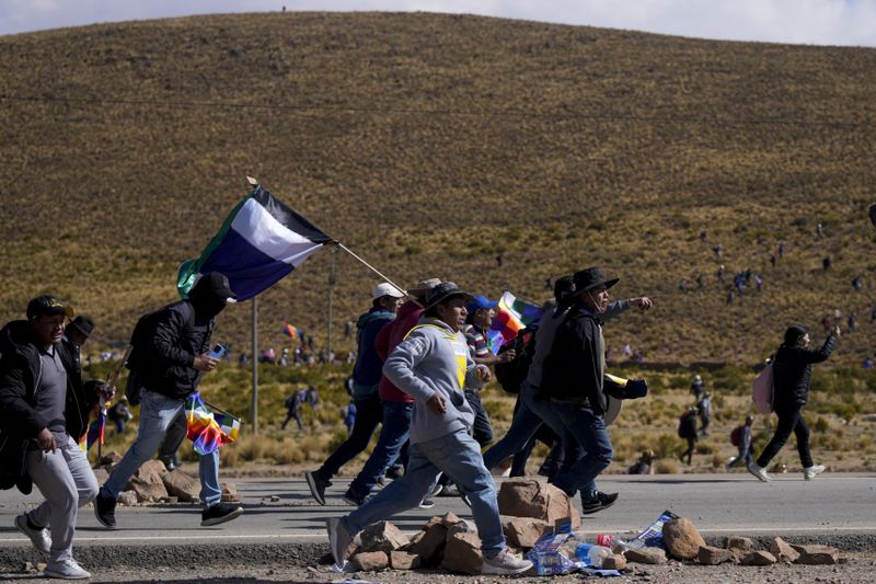 Supporters of former President Evo Morales, who are marching to the capital to protest the government of current President Luis Arce, run towards Arce supporters, in Vila Vila, Bolivia Tuesday, Sept. 17, 2024. (AP Photo/Juan Karita)