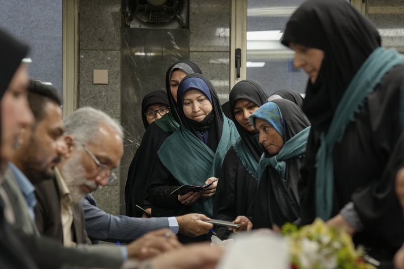Iranian women wait in queue to cast their votes during the presidential election at a polling station inside the Iranian embassy in Baghdad, Iraq, Friday, June 28, 2024. Iranians are voting in a presidential election to replace the late President Ebrahim Raisi, killed in a helicopter crash in May along with the country's foreign minister and several other officials. (AP Photo/Hadi Mizban)