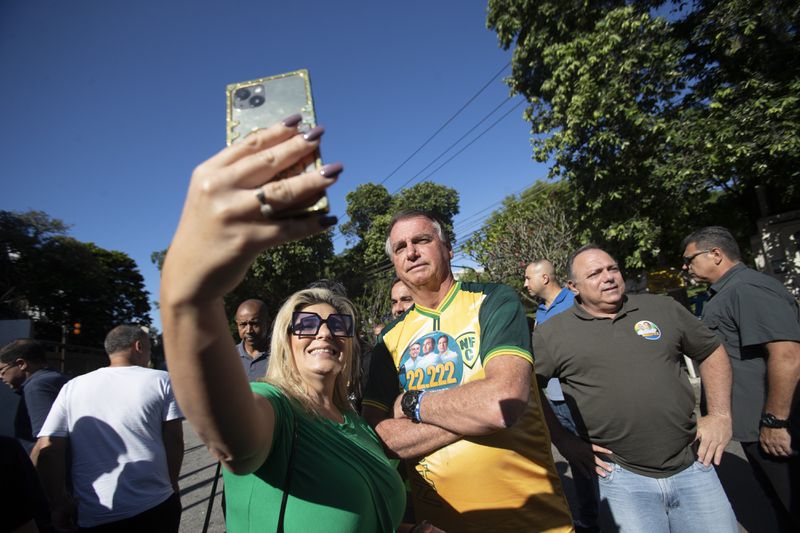 A supporter takes a selfie with former President Jair Bolsonaro as he accompanies Rio de Janeiro mayoral candidate Alexandre Ramagem during the municipal elections in Rio de Janeiro, Sunday, Oct. 6, 2024. (AP Photo/Bruna Prado)