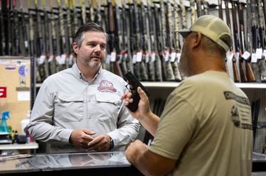 Adventure Outdoors general manager and part-owner Eric Wallace, left, helps Bobby Gibbs decide on a potential gun purchase in Smyrna on Tuesday, July 23, 2024. Sales are up substantially, according to Wallace. “A lot of our customers are saying that if the Secret Service, which is known to be one of the best law enforcement agencies in the world, can’t protect a former president, how is our government going to protect us if something serious were to happen?” Wallace said.  (Steve Schaefer / AJC)