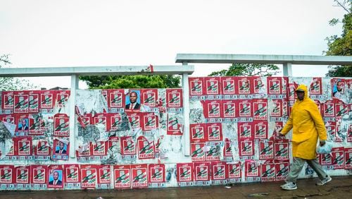 A pedestrian passes a wall of election posters in Maputo, Sunday, Oct. 6, 2024, ahead of elections to be held in Mozambique. (AP Photo/Carlos Uqueio)