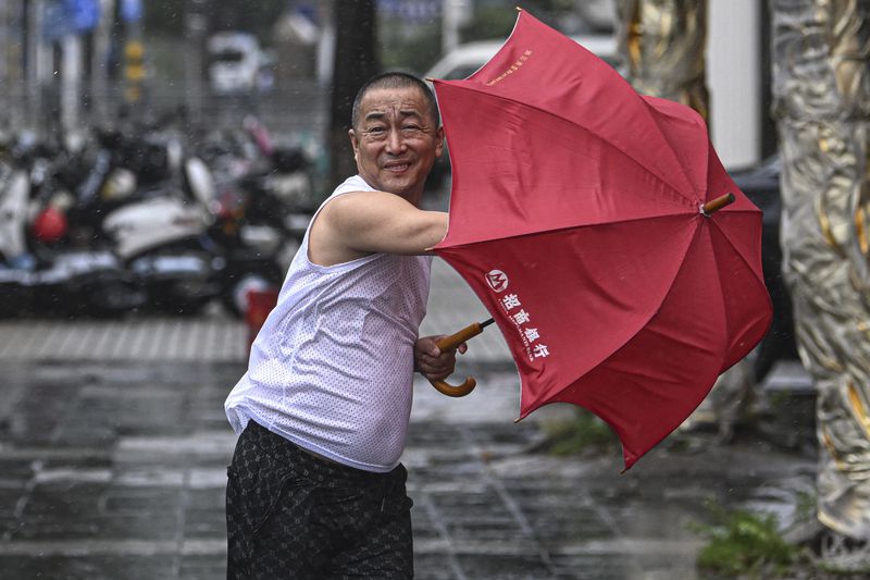 In this photo released by Xinhua News Agency, a man holding an umbrella struggles against the wind following the landfall of typhoon Yagi in Haikou, south China's Hainan Province, Friday, Sept. 6, 2024. (Pu Xiaoxu/Xinhua via AP)