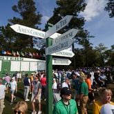 Patrons walk around a sign posting directions to famous areas of interest such as; Amen Corner, with the Masters scoreboard in the background near the first fairway during the practice round of the 2024 Masters Tournament at Augusta National Golf Club, Wednesday, April 10, 2024, in Augusta, Ga. (Jason Getz / jason.getz@ajc.com)