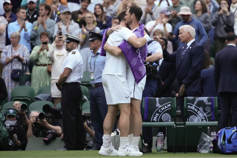 Britain's Andy Murray, left, hugs his brother Jamie following their first round doubles match against Australia's John Peers and Ricky Hijikata at the Wimbledon tennis championships in London, Thursday, July 4, 2024. (AP Photo/Kirsty Wigglesworth)