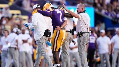 LSU head coach Brian Kelly, right, pats linebacker Harold Perkins Jr. (7) as he is helped off the field after being injured in the second half of an NCAA college football game against UCLA in Baton Rouge, La., Saturday, Sept. 21, 2024. LSU won 34-17. (AP Photo/Gerald Herbert)