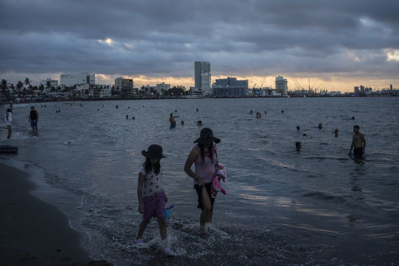 A woman and a girl walk along the shore to cool off during the heat wave on the coast of Veracruz, Mexico, on June 15, 2024. Human-caused climate change intensified and made far more likely this month's killer heat with triple digit temperatures, a new flash study found Thursday, June 20. (AP Photo/Felix Marquez)
