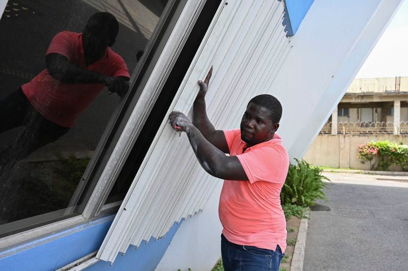 A man covers the windows of a building to protect it from the incoming Hurricane Beryl in Kingston, Jamaica, Tuesday, July 2, 2024. (AP Photo/Collin Reid)