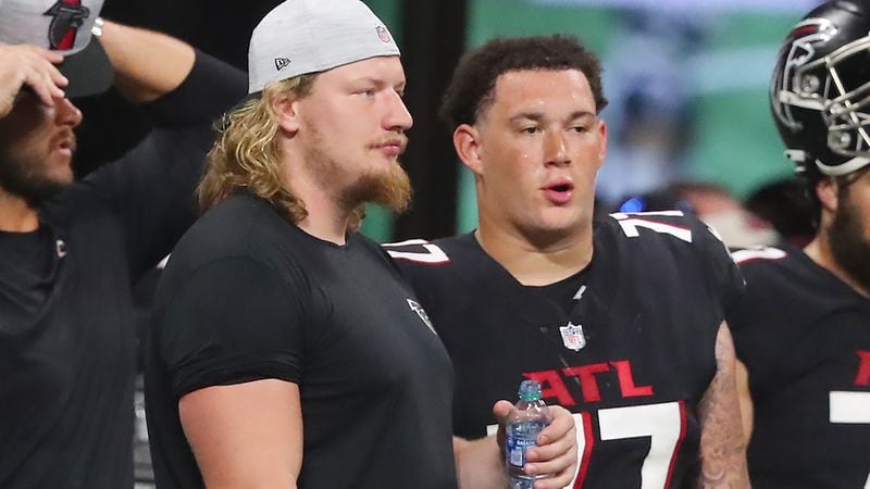 Falcons offensive lineman Kaleb McGary (left) watches from the sidelines with rookie offensive lineman Jalen Mayfield as the Falcons face the Tennessee Titans in a preseason game Friday, Aug. 13, 2021, at Mercedes-Benz Stadium in Atlanta. (Curtis Compton / Curtis.Compton@ajc.com)