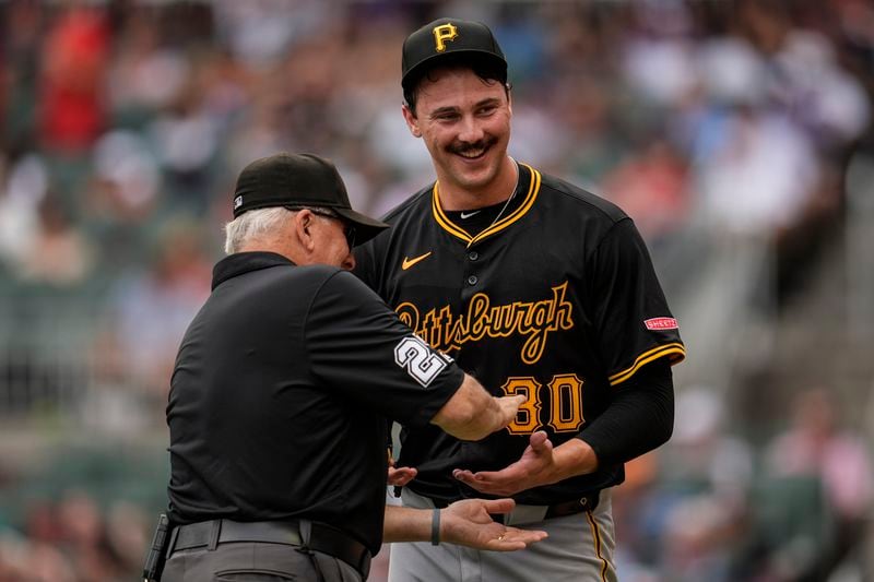 An official checks the glove and hands of Pittsburgh Pirates pitcher Paul Skenes (30) in the third inning of a baseball game against the Atlanta Braves, Saturday, June 29, 2024, in Atlanta. (AP Photo/Mike Stewart)