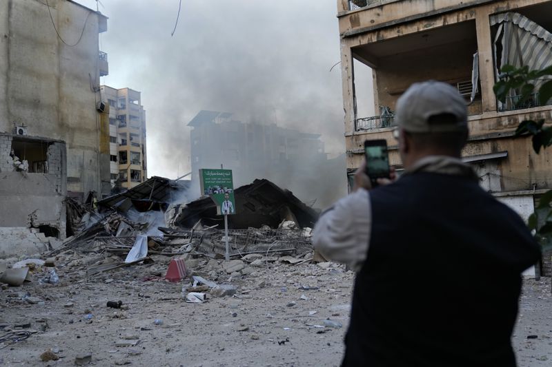 A man takes pictures of a destroyed building hit by Israeli airstrike in Dahiyeh, Beirut, Lebanon, Sunday, Oct. 6, 2024. (AP Photo/Hussein Malla)