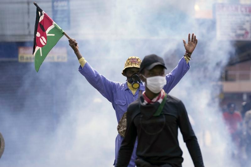 An anti-government protester waves a Kenyan flag as police fire teargas at them during a protest over proposed tax hikes in a finance bill in downtown Nairobi, Kenya Tuesday, June. 25, 2024. (AP Photo/Brian Inganga)