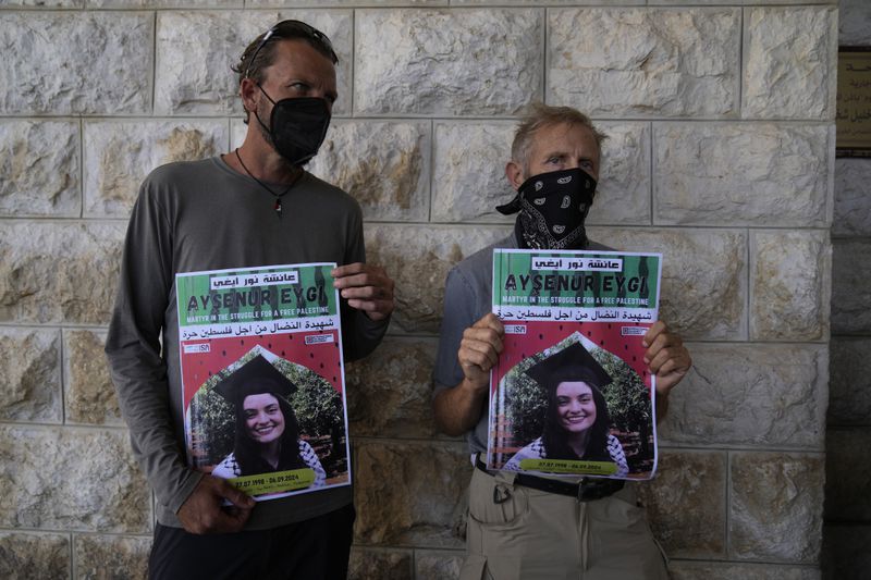 Two fellow activists of Aysenur Ezgi Eygi, 26, who was fatally shot by Israeli soldiers while participating in an anti-settlement protest in the West Bank, carry posters with her name and photo during Eygi's funeral procession in the West Bank city of Nablus, Monday, Sept. 9, 2024. (AP Photo/Nasser Nasser)