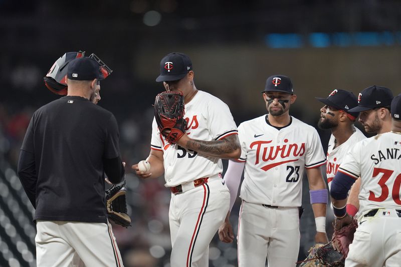 Minnesota Twins relief pitcher Jhoan Duran, center left, hands the ball to manager Rocco Baldelli for a pitching change during the 10th inning of a baseball game against the Atlanta Braves, Tuesday, Aug. 27, 2024, in Minneapolis. (AP Photo/Abbie Parr)