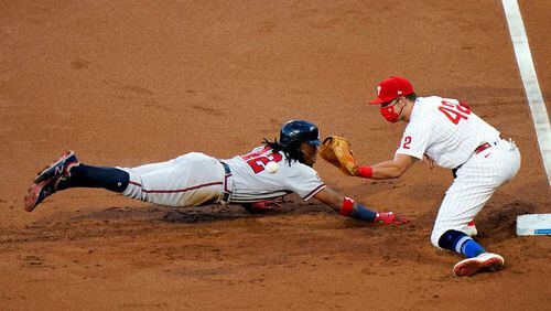 Braves outfielder Ronald Acuna dives safely back to first base as Phillies first baseman Rhys Hoskins catches a pick-off throw during the first inning Sunday, Aug. 30, 2020, in Philadelphia.