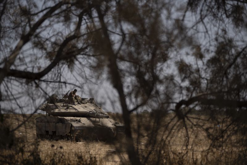 An Israeli soldier sits on the top of a tank near the Israeli-Gaza border, as seen from southern Israel, Saturday, June 29, 2024. (AP Photo/Leo Correa)