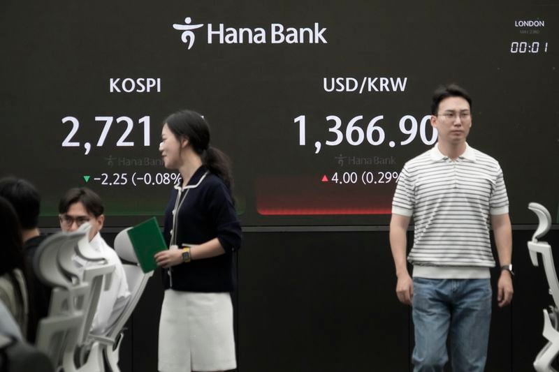 Currency traders pass by the screen showing the Korea Composite Stock Price Index (KOSPI), left, and the foreign exchange rate between U.S. dollar and South Korean won at the foreign exchange dealing room of the KEB Hana Bank headquarters in Seoul, South Korea, Thursday, May 23, 2024. (AP Photo/Ahn Young-joon)
