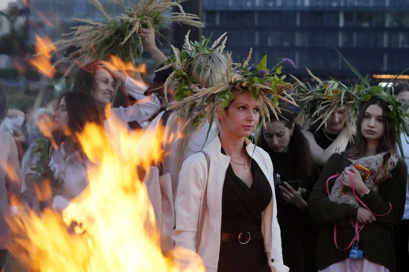 Ukrainian women wear ear of grain braids during traditional Ukrainian celebration of Kupalo Night, in Warsaw, Poland, on Saturday, June 22, 2024. Ukrainians in Warsaw jumped over a bonfire and floated braids to honor the vital powers of water and fire on the Vistula River bank Saturday night, as they celebrated their solstice tradition of Ivan Kupalo Night away from war-torn home. (AP Photo/Czarek Sokolowski)