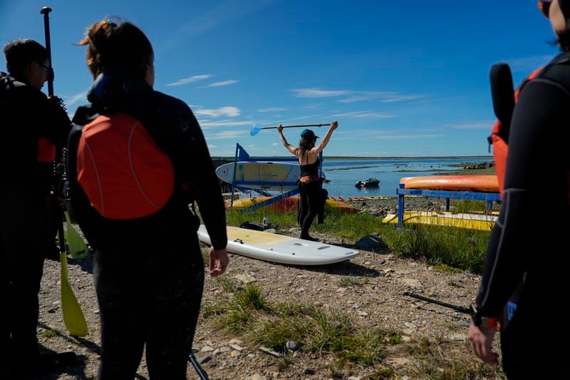 Erin Greene, center, owner of Sup North, demonstrates proper use of a paddle before leading a paddleboarding tour, Thursday, Aug. 8, 2024, in Churchill, Manitoba. (AP Photo/Joshua A. Bickel)