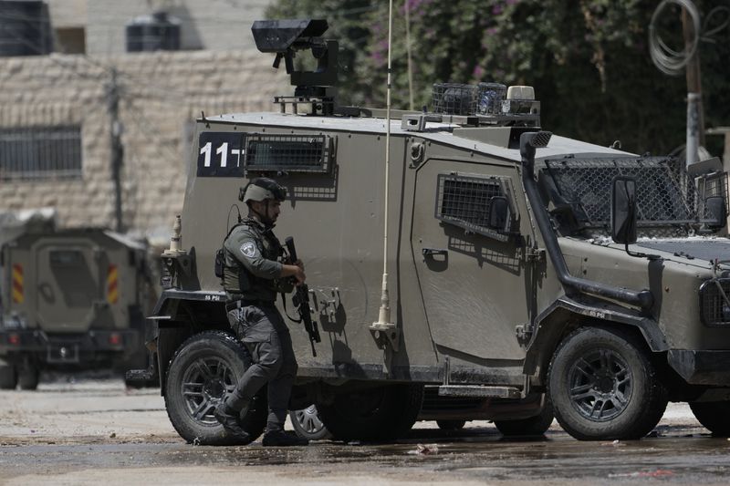 A member of the Israeli forces walks next to an armoured vehicle during a military operation in the West Bank city of Jenin, Wednesday, Aug. 28, 2024. (AP Photo/Majdi Mohammed)