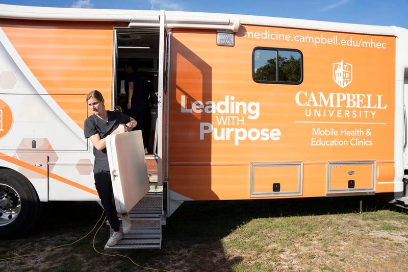 Claudia Lenhart, 25, a second-year Campbell University medical student, helps set up a mobile health clinic organized by NC FIELD outside María, Reina de las Américas Catholic Church in Mt. Olive, N.C., on Wednesday, June 19, 2024. The mobile clinic is adapted to treat rural patients, many of them agricultural workers, who often work during normal office hours, lack health insurance and face language barriers. (Angelica Edwards/Enlace Latino NC, CatchLight Local via AP)