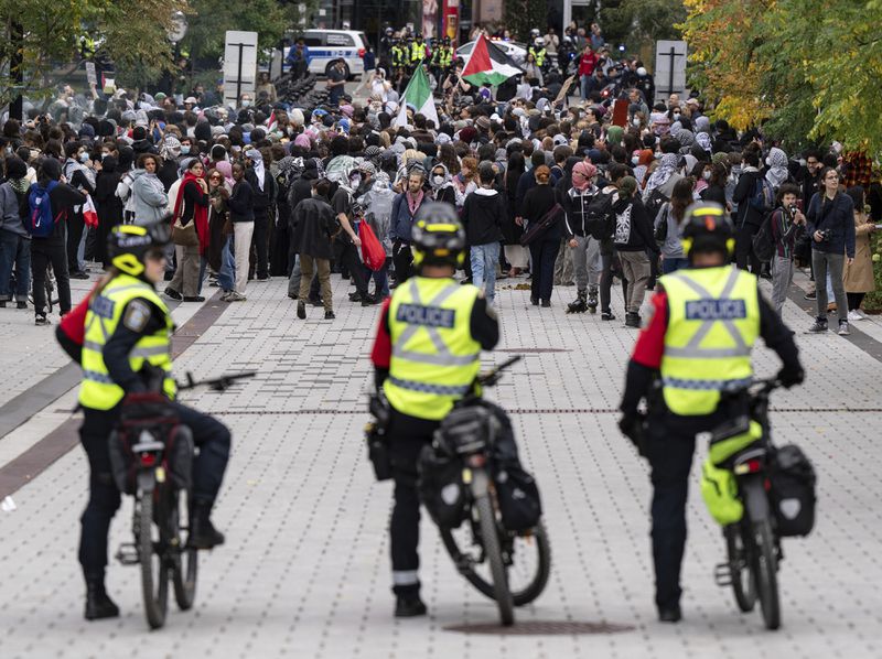 Police watch as attendees march near McGill University campus during a pro-Palestinian demonstration on the anniversary of a Hamas attack on Israel that triggered the ongoing war in Gaza, in Montreal, Canada, Monday, Oct. 7, 2024. (Christinne Muschi/The Canadian Press via AP)