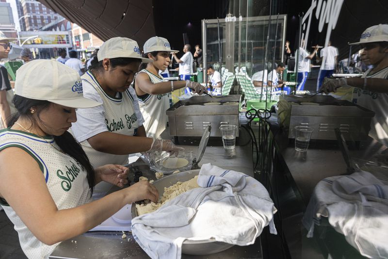 Students from Food and Finance high school make taco dough during a summer block party outside the Barclays Center, Thursday, July. 11, 2024, in New York. (AP Photo/Jeenah Moon)