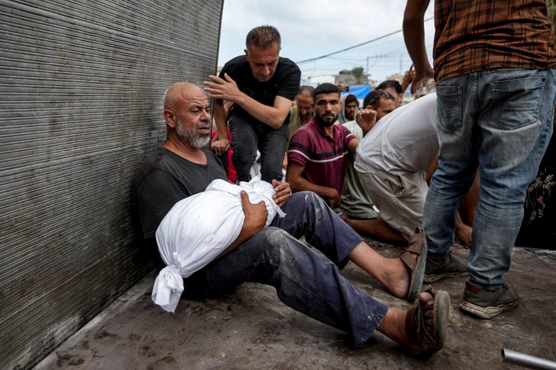 A Palestinian man holds the body of a relative killed in the Israeli bombardment of the Gaza Strip, at a hospital in Deir al-Balah, Thursday, Aug. 22, 2024. (AP Photo/Abdel Kareem Hana)