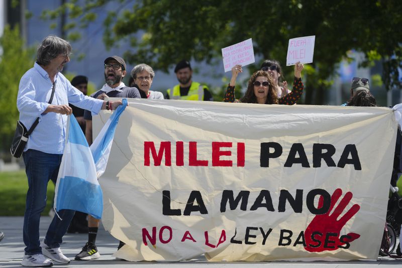 Demonstrators show banners and posers as they protest against the visit Argentina's President Javier Milei for a meeting at the chancellery to meet German Chancellor Olaf Scholz in Berlin, Germany, Sunday, June 23, 2024. Banner and posters read: 'Milei for the hand, no to the base law', 'Milei saif soizialism in the cancer of humanity', 'Milei out'. (AP Photo/Markus Schreiber)