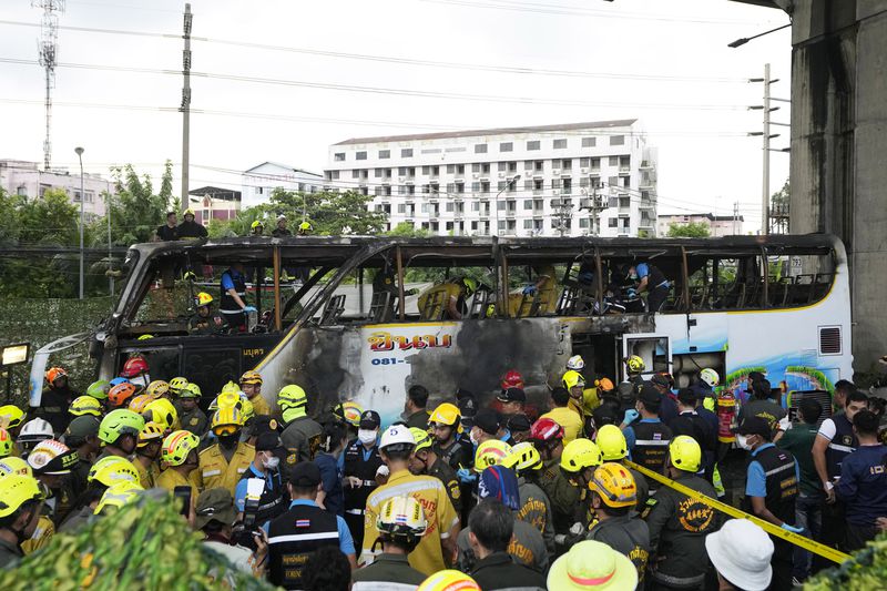 Rescuer inspect a bus which caught fire as it was carrying young students with their teachers, in suburban Bangkok, Tuesday, Oct. 1, 2024. (AP Photo/Sakchai Lalit)