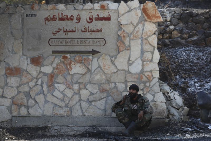 A Syrian soldier smokes a cigaret, as he sits on the ground in the town of Masyaf, Syria, Monday, Sept. 9, 2024. Syrian state news agency SANA says that Israeli strikes hit several areas in central Syria Sunday night, damaging a highway in Hama province and sparking fires. (AP Photo/Omar Sanadiki)