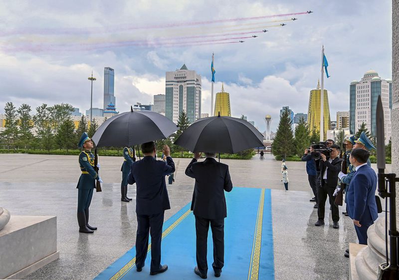 In this photo released by Kazakhstan's Presidential Press Office, President Kassym-Jomart Tokayev, right back to camera, and Chinese President Xi Jinping, left back to camera, pose for a photo as they arrive to attend an official welcome ceremony at the palace in Astana, Kazakhstan, on Wednesday, July 3, 2024. (Kazakhstan's Presidential Press Office via AP)