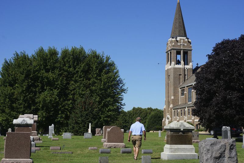 Jeff Davidson, a member of Holden Lutheran Church near Kenyon, Minn, walks through the church cemetery where half a dozen generations of his family are buried in the farmland near Kenyon, Minn, on Sept. 1, 2024. (AP Photo/Giovanna Dell'Orto)