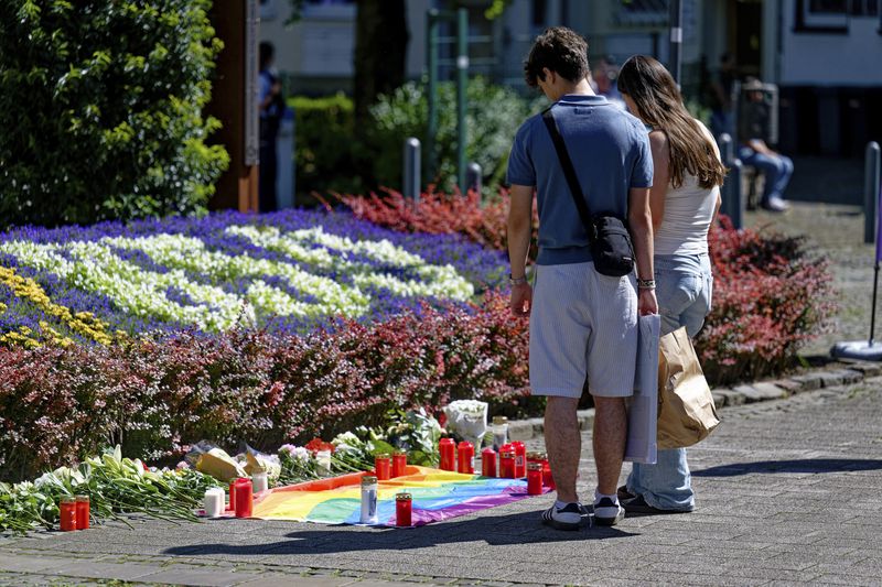 People lay flowers near the scene of a knife attack in Solingen city center, Germany, Saturday Aug. 24, 2024, after three people were killed and at least eight people were wounded Friday night at the festival. (Henning Kaiser/dpa via AP)