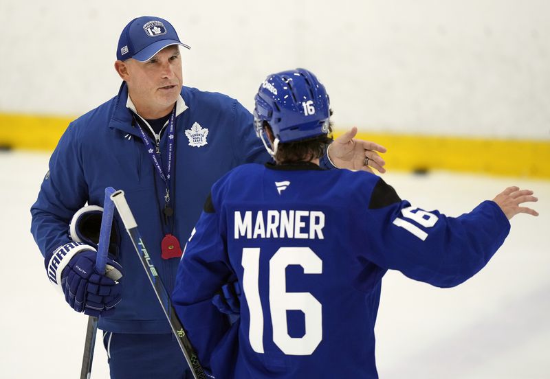 Toronto Maple Leafs new head coach Craig Berube, left, talks with forward Mitch Marner during NHL training camp in Toronto, Thursday, Sept. 19, 2024. (Nathan Denette/The Canadian Press via AP)